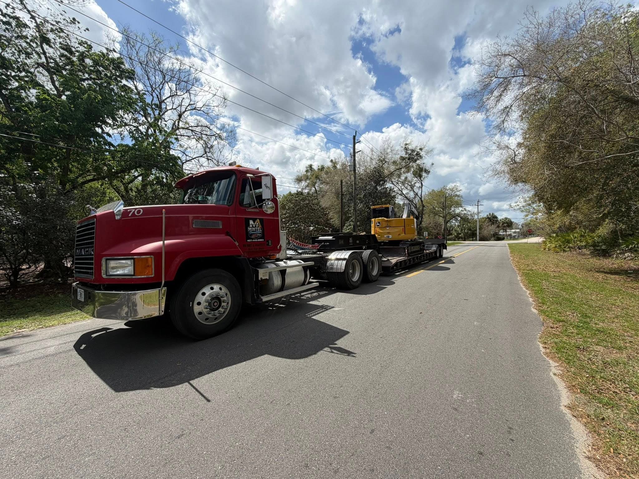 Mintel Land Management lowboy trailer hauling heavy machines to a Central Florida job site
